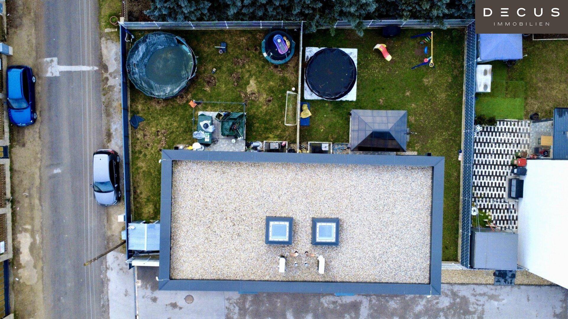 Luftaufnahme des Hauses mit Flachdach, Garten, zwei Pools und umliegender Nachbarschaft.