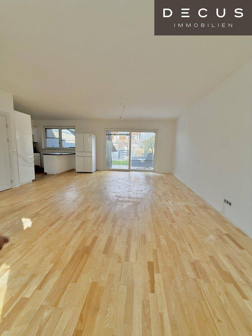 Heller offener Wohnbereich mit Parkettboden und Zugang zur Terrasse.