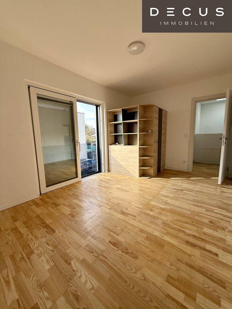 Geräumiger Raum mit Parkettboden und großem Schiebefenster zum Außenbereich.