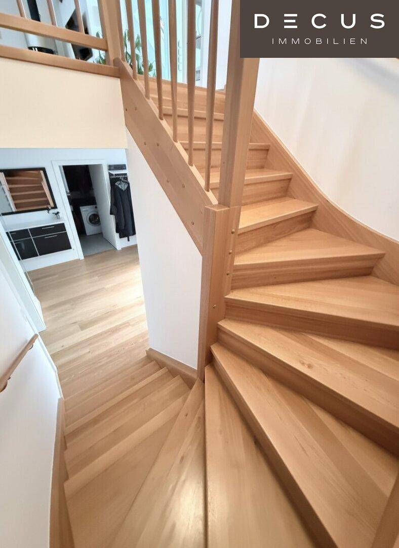 Helle Holztreppe mit modernem Geländer, die die verschiedenen Ebenen der Wohnung verbindet.