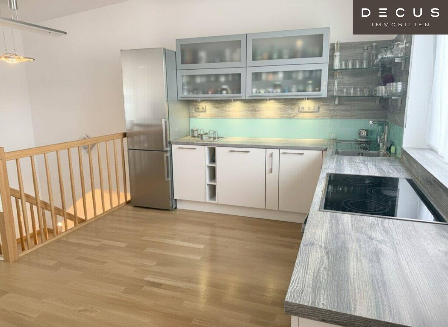 Funktionale Küche mit Induktionskochfeld, Kühlschrank und viel Stauraum, offen gestaltet und hell.