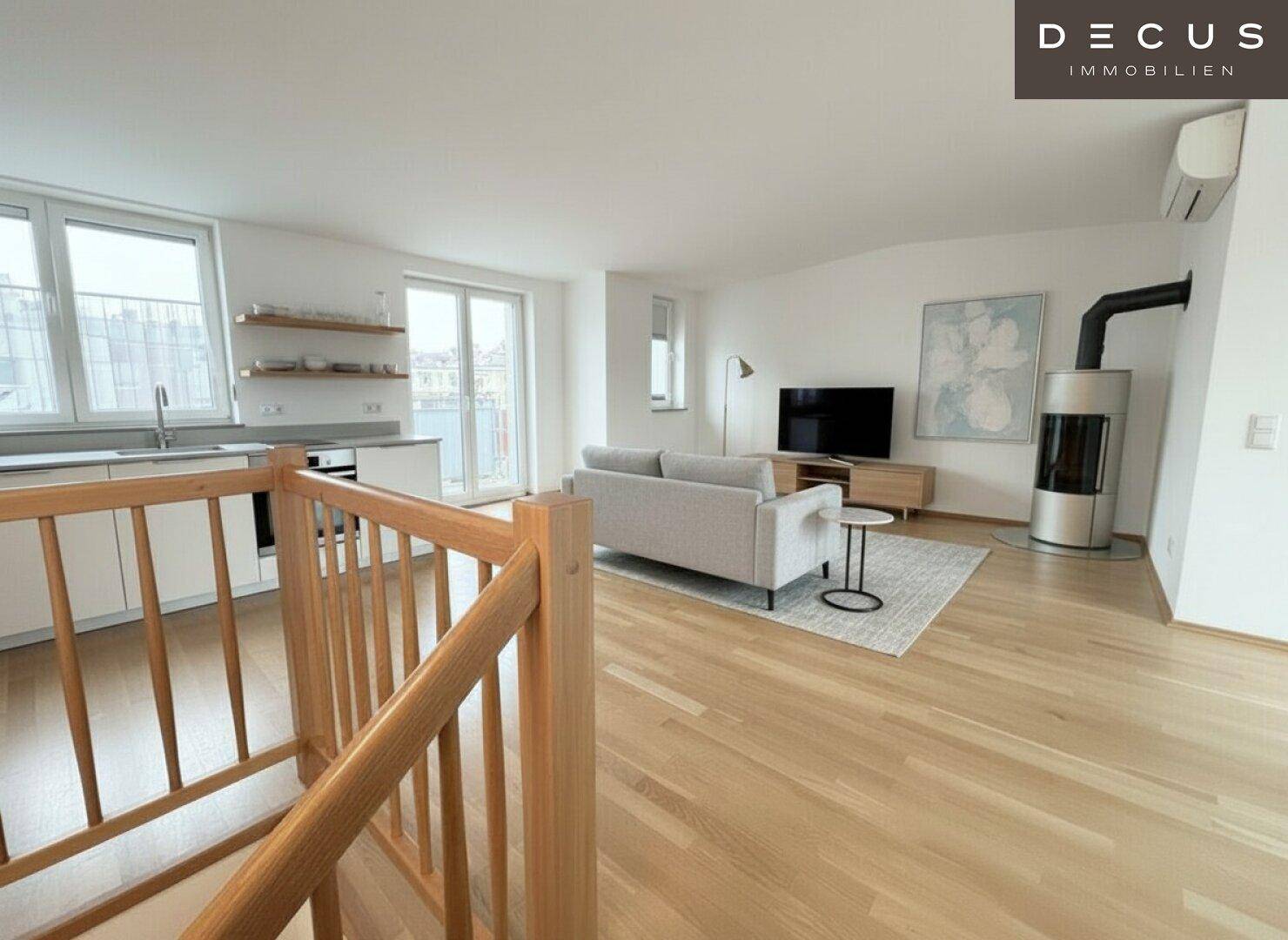 Offener Wohnbereich mit Holzboden, Kaminofen und Blick auf die integrierte Küche, hell und modern.