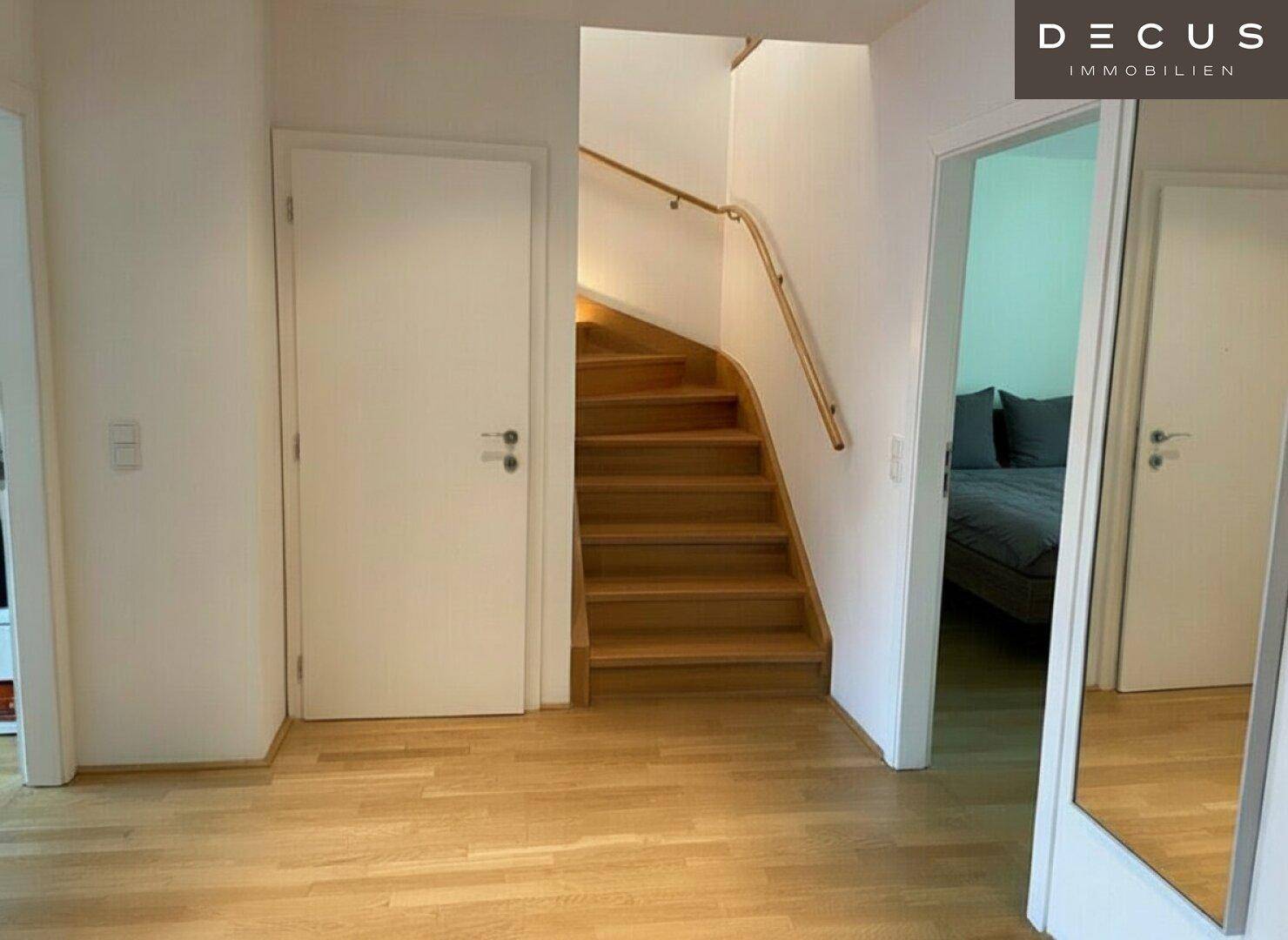 Eingangsbereich mit Holzboden und einer geschwungenen Holztreppe, die zu den oberen Etagen führt.