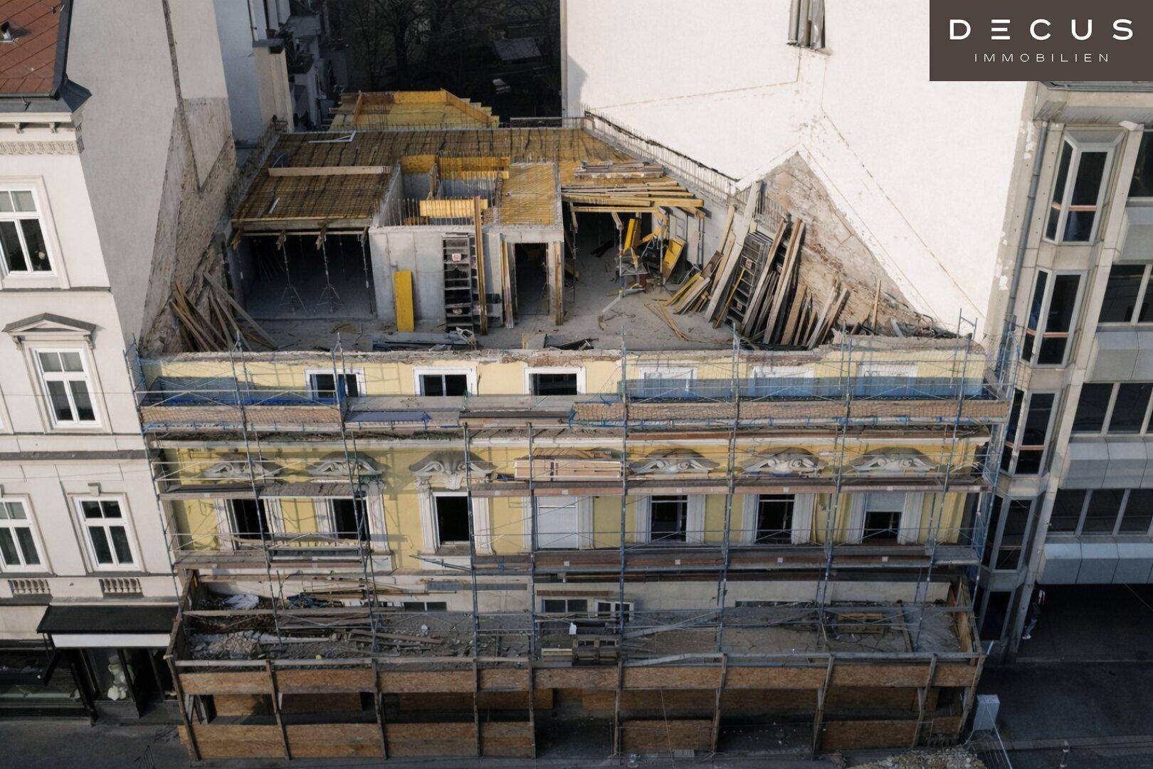 Gebäude im Bauzustand mit Gerüst und sichtbaren Bauelementen in urbaner Umgebung.