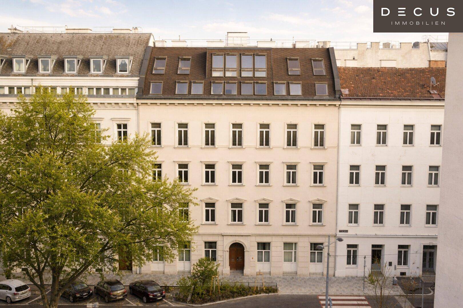 Historisches Gebäude mit modernem Dachausbau und vielen Fenstern, integriert in eine städtische Häuserzeile.