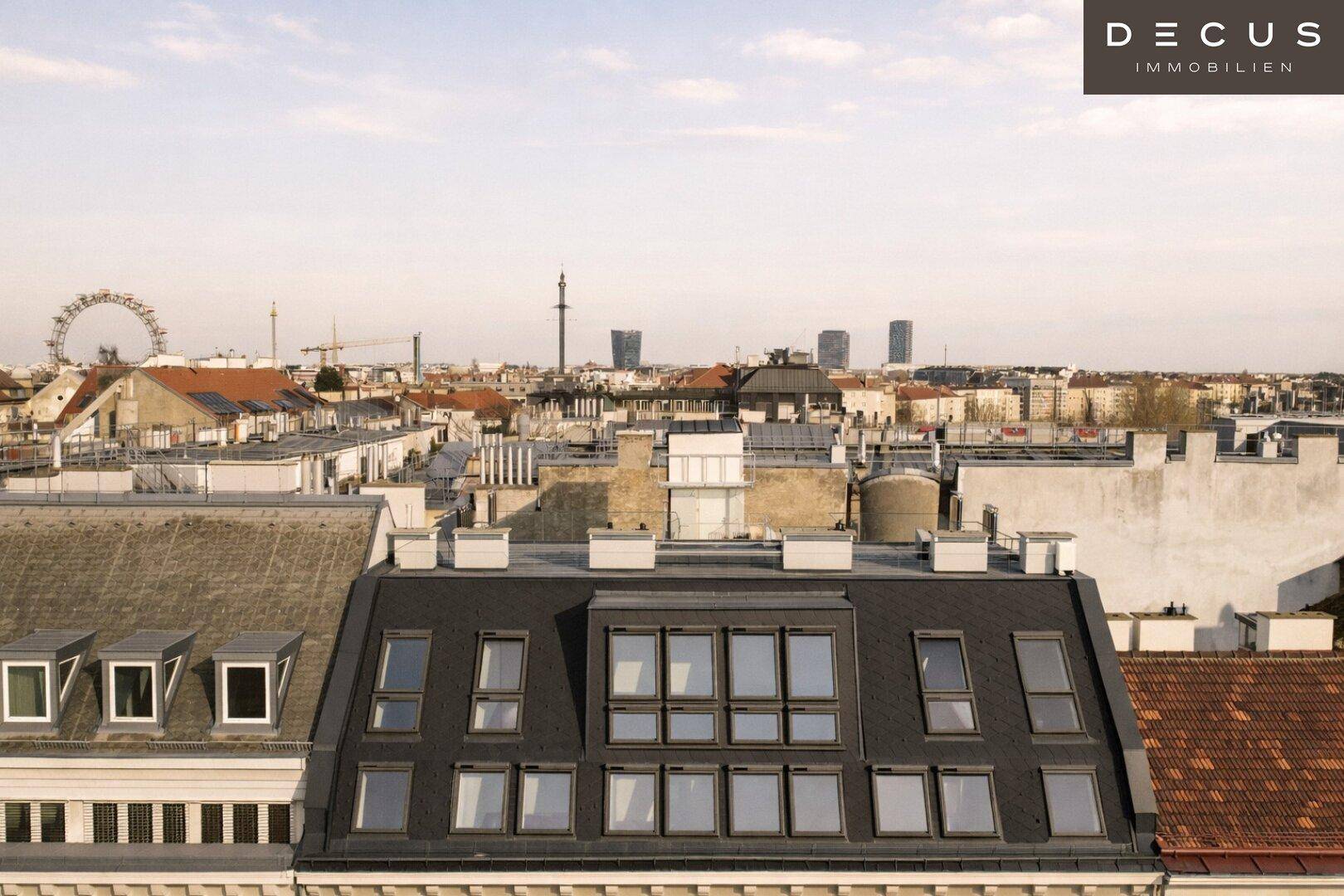 Panoramablick über die Stadt mit Dächern und urbaner Skyline, inklusive Riesenrad in der Ferne.