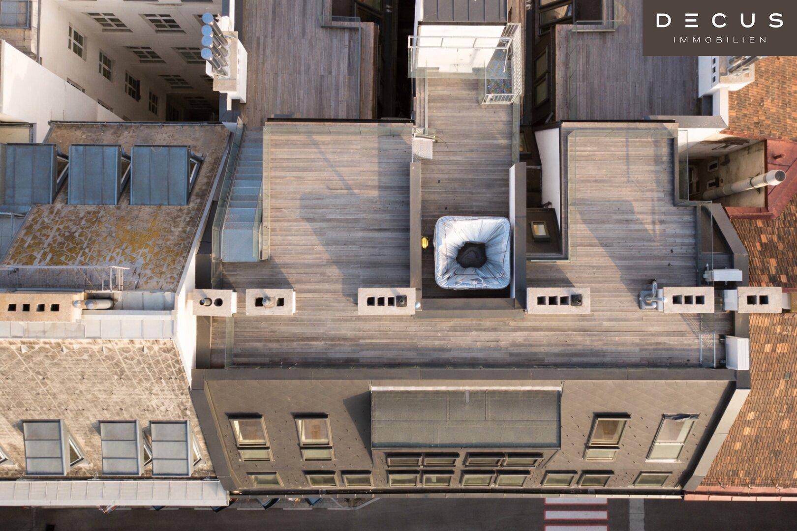 Luftaufnahme der Dächer mit Dachterrassen und Whirlpool, zeigt die urbane Struktur von oben.