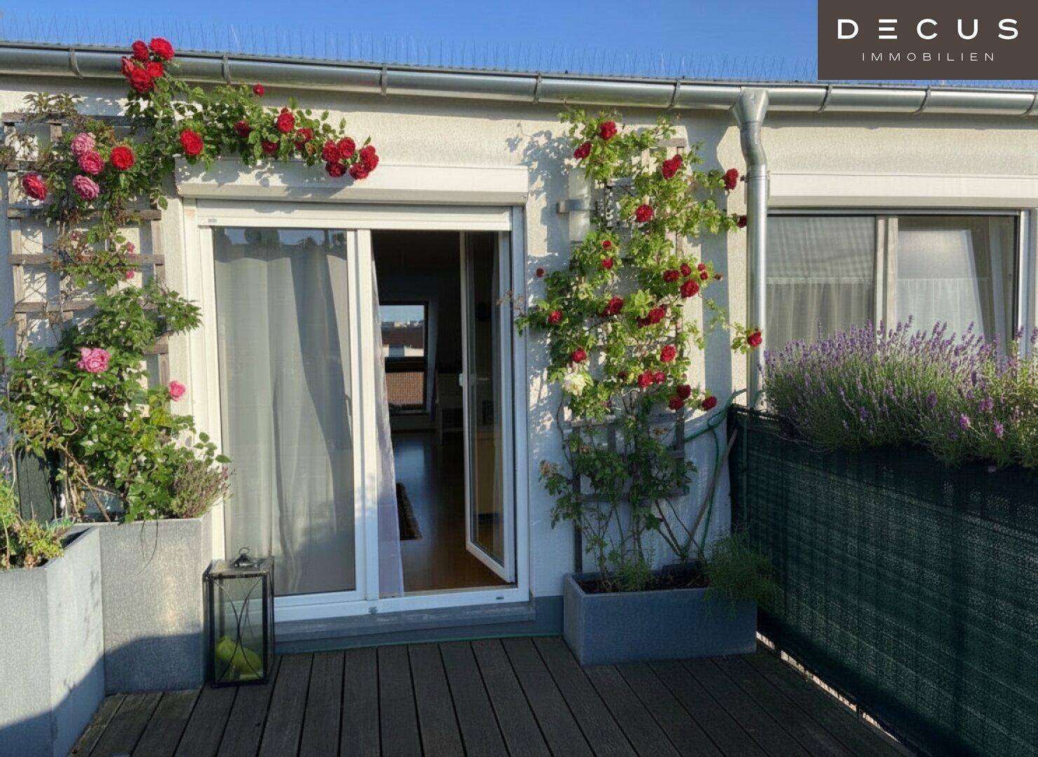 Sonniger Terrassenbereich mit blühenden Rosen, Lavendel und Holzboden.