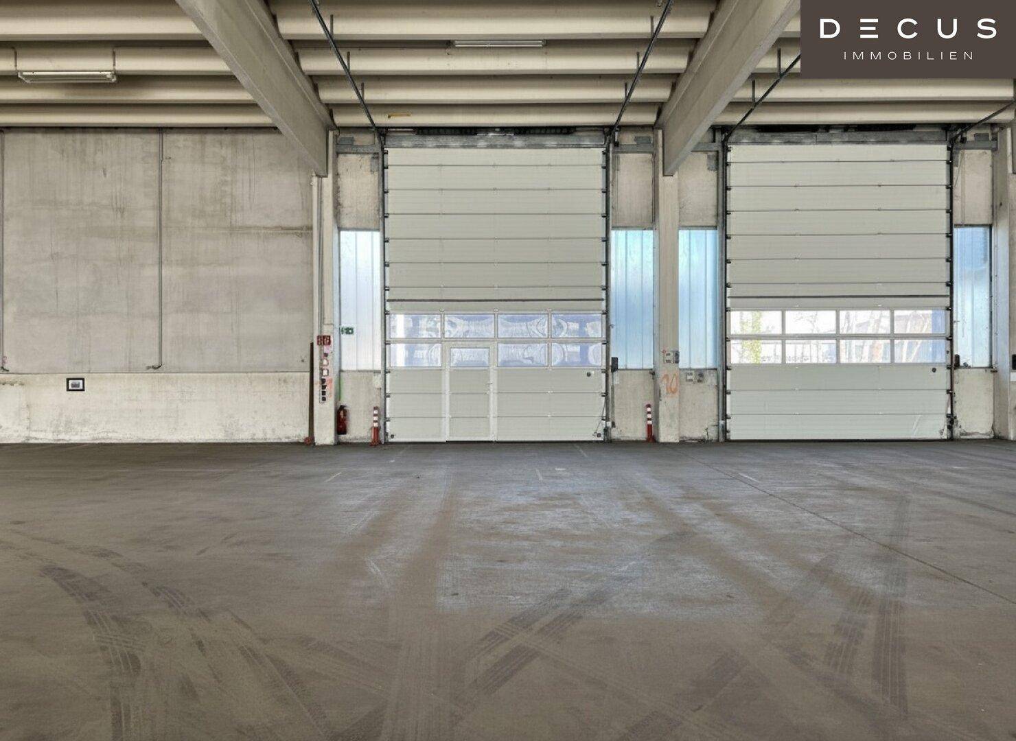 Detailansicht der zwei großen Rolltore in einer geräumigen Lagerhalle mit Betonboden.