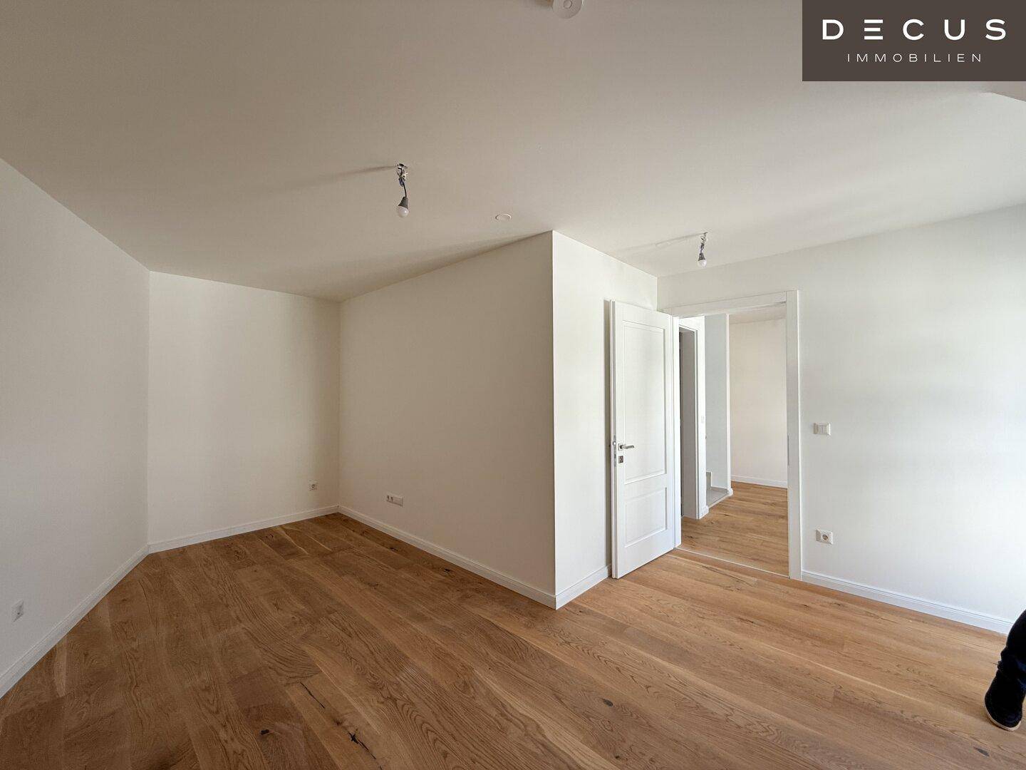 Leerer Raum mit hellem Holzparkettboden und weißen Wänden, bereit zur individuellen Gestaltung.