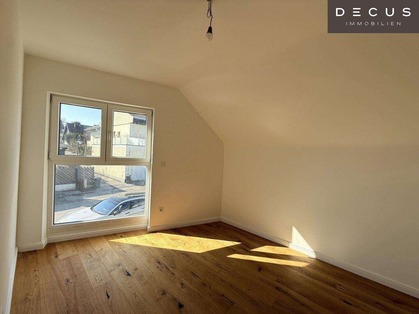 Lichtdurchfluteter Raum im Dachgeschoss mit Holzboden und schräger Decke, ideal als Schlafzimmer.