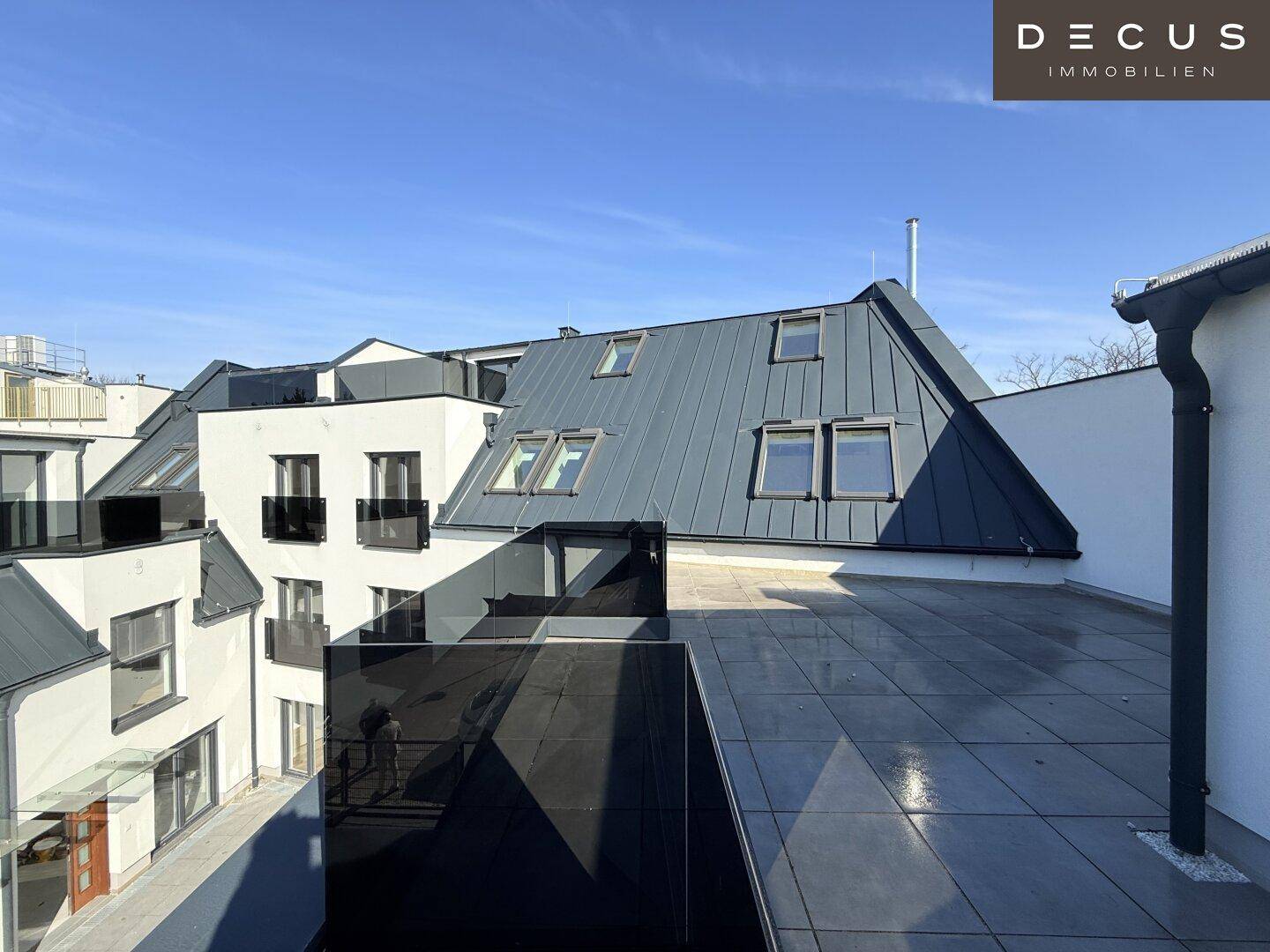 Blick auf die moderne Architektur des Gebäudes mit Dachterrasse und Schrägdächern.