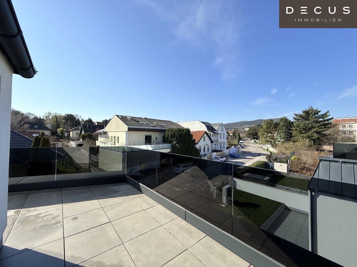 Geräumige Terrasse mit Glasgeländer und weitem Blick auf die umliegende Wohngegend.