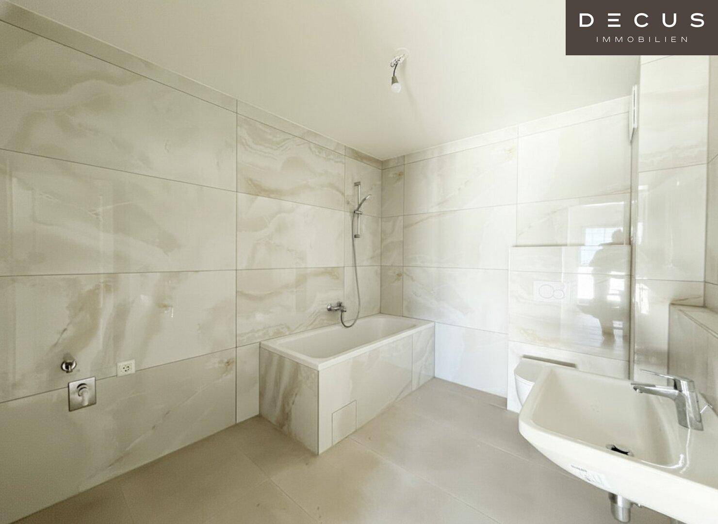 Modernes Badezimmer mit hellen Fliesen, Badewanne und Waschbecken, in neuwertigem Zustand.