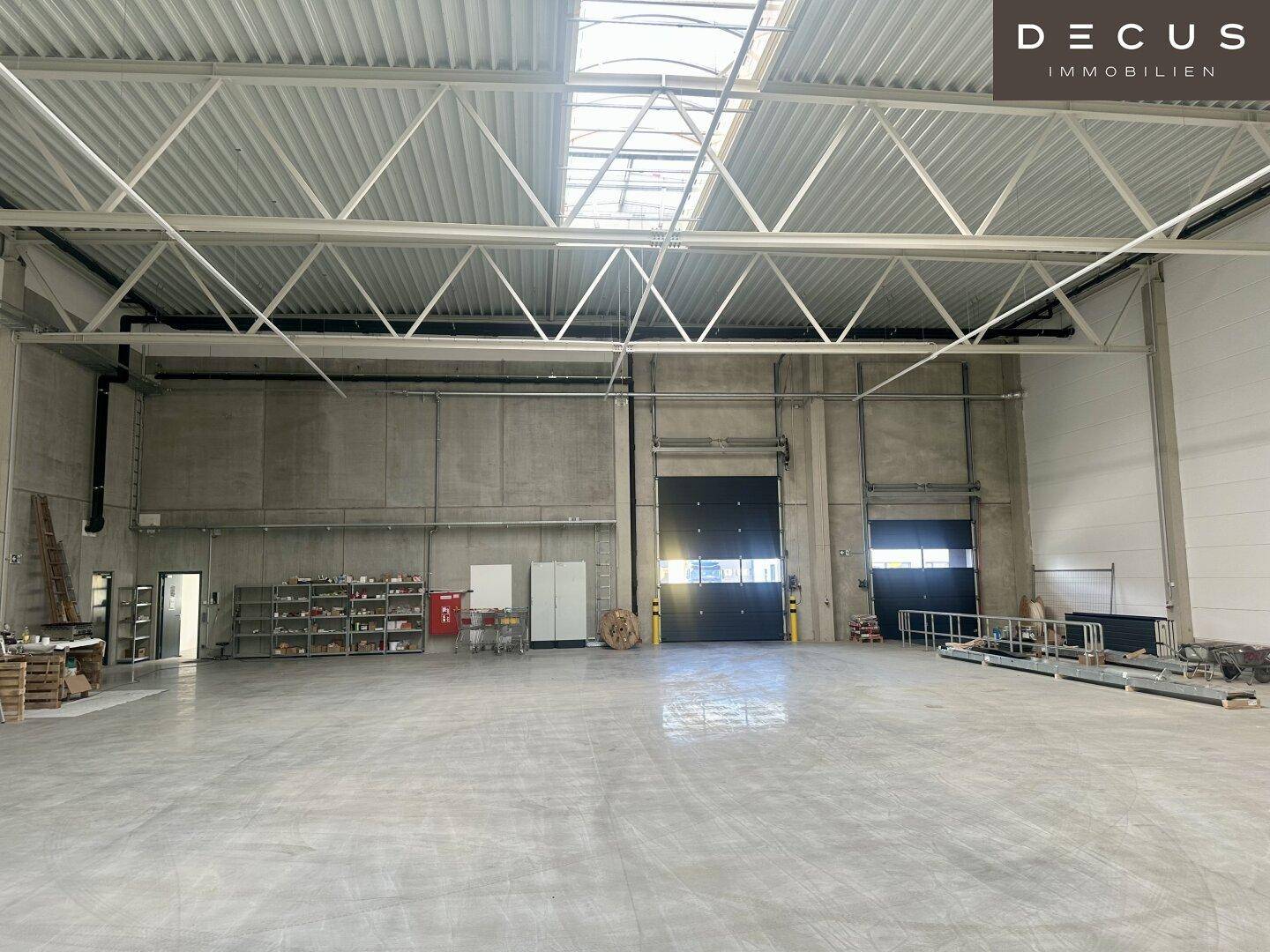 Innenansicht der Lagerhalle mit großem Rolltor, Betonwänden und Regalsystemen im Hintergrund.