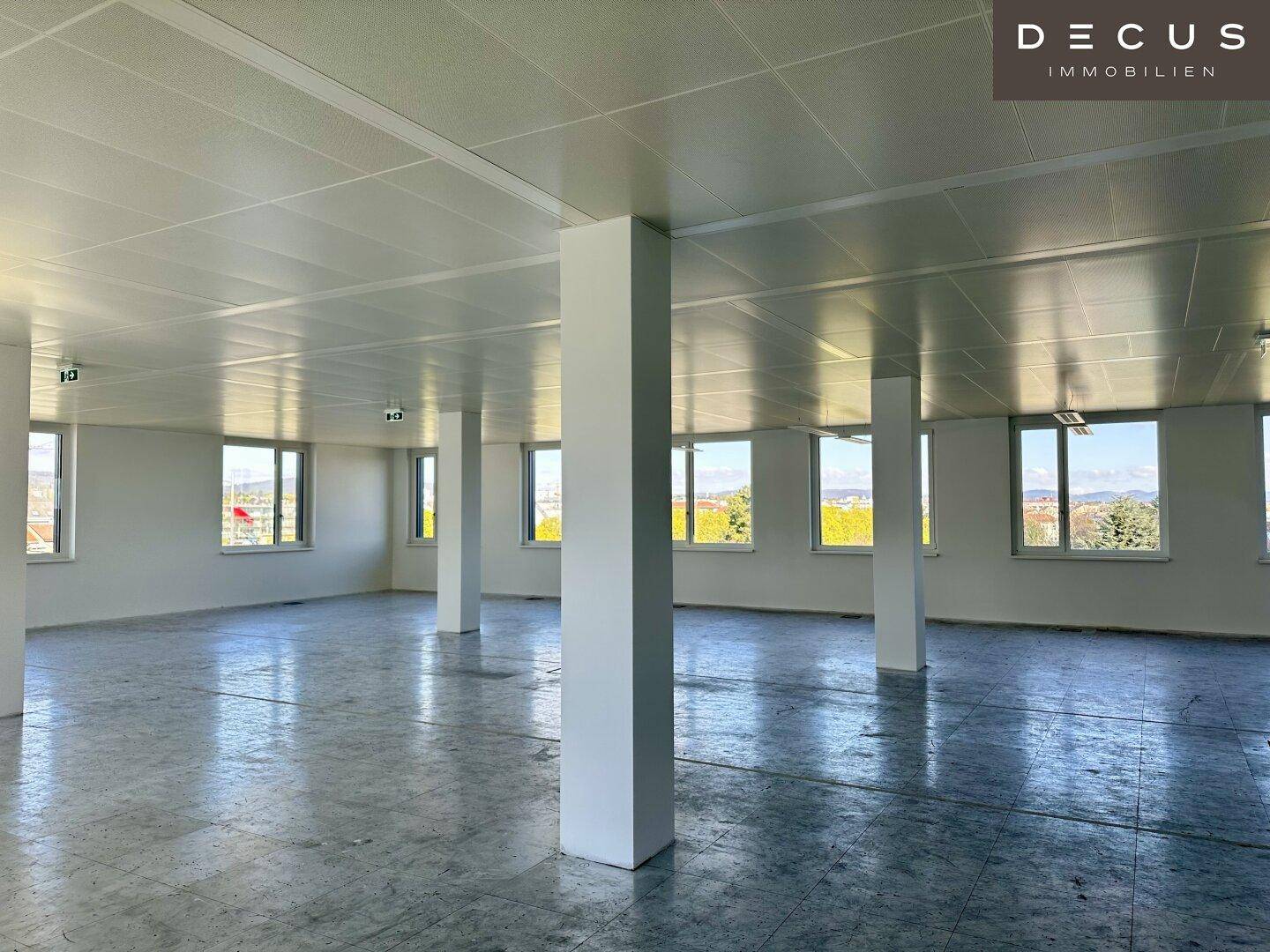 Heller und geräumiger Büroraum mit zahlreichen Fenstern, die eine weite Aussicht auf die Umgebung bieten.
