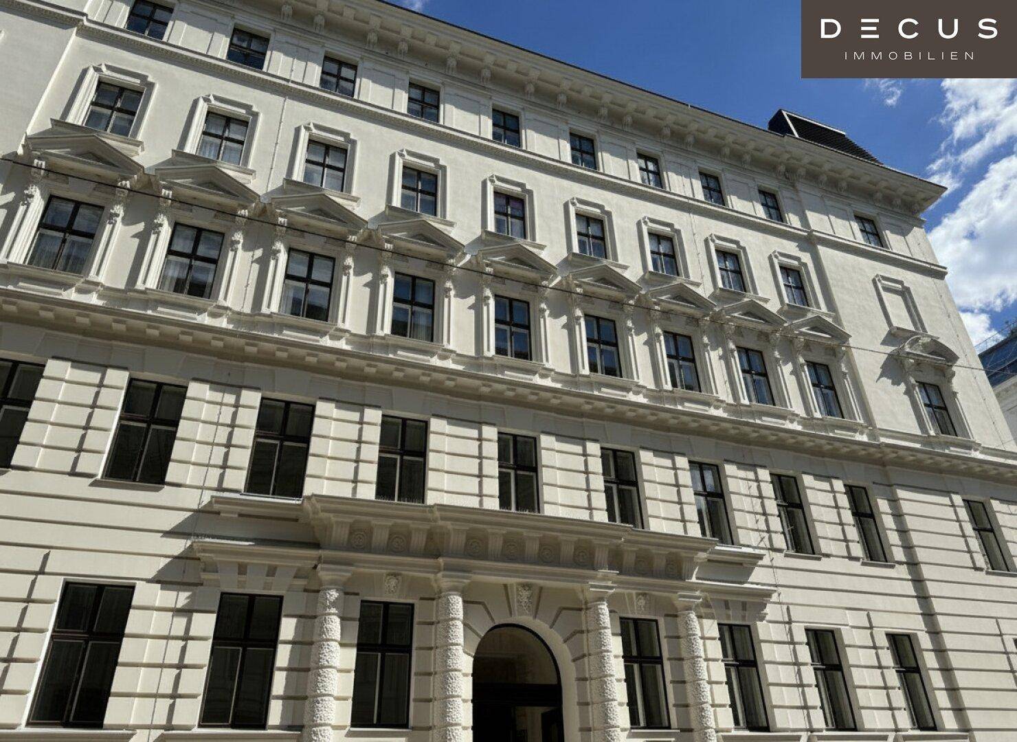 Elegante Fassade eines historischen Gebäudes mit detaillierten Verzierungen und vielen Fenstern.