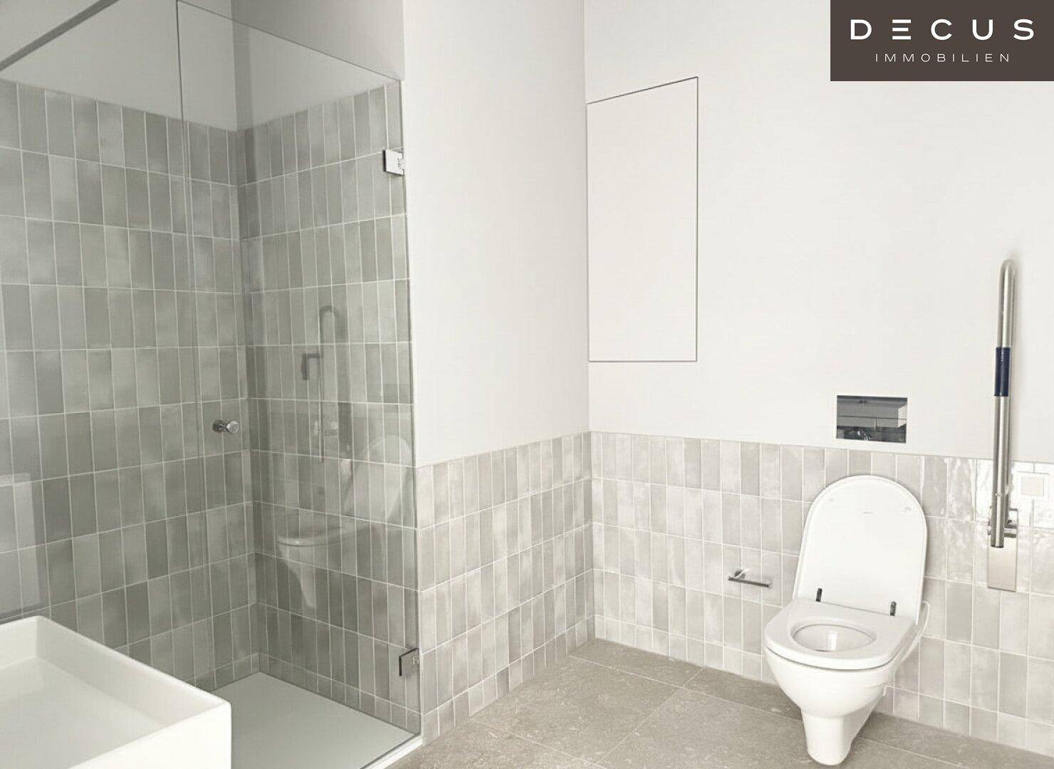 Modernes Badezimmer mit grauen Fliesen, einer begehbaren Dusche und einem wandhängenden WC.