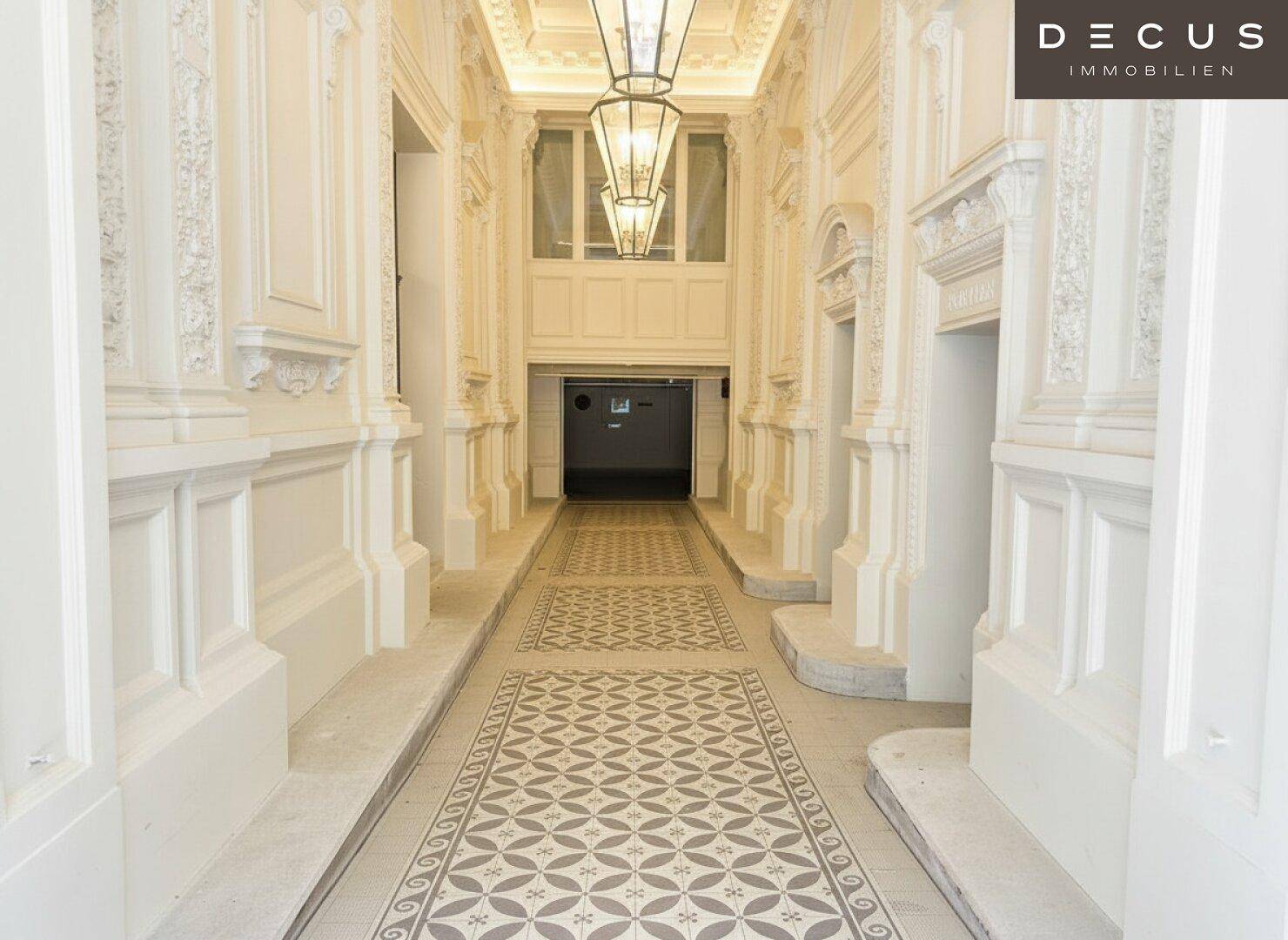 Prunkvoller Flur mit hohen Decken, dekorativen Elementen und eleganten Hängelampen in einem Altbau.