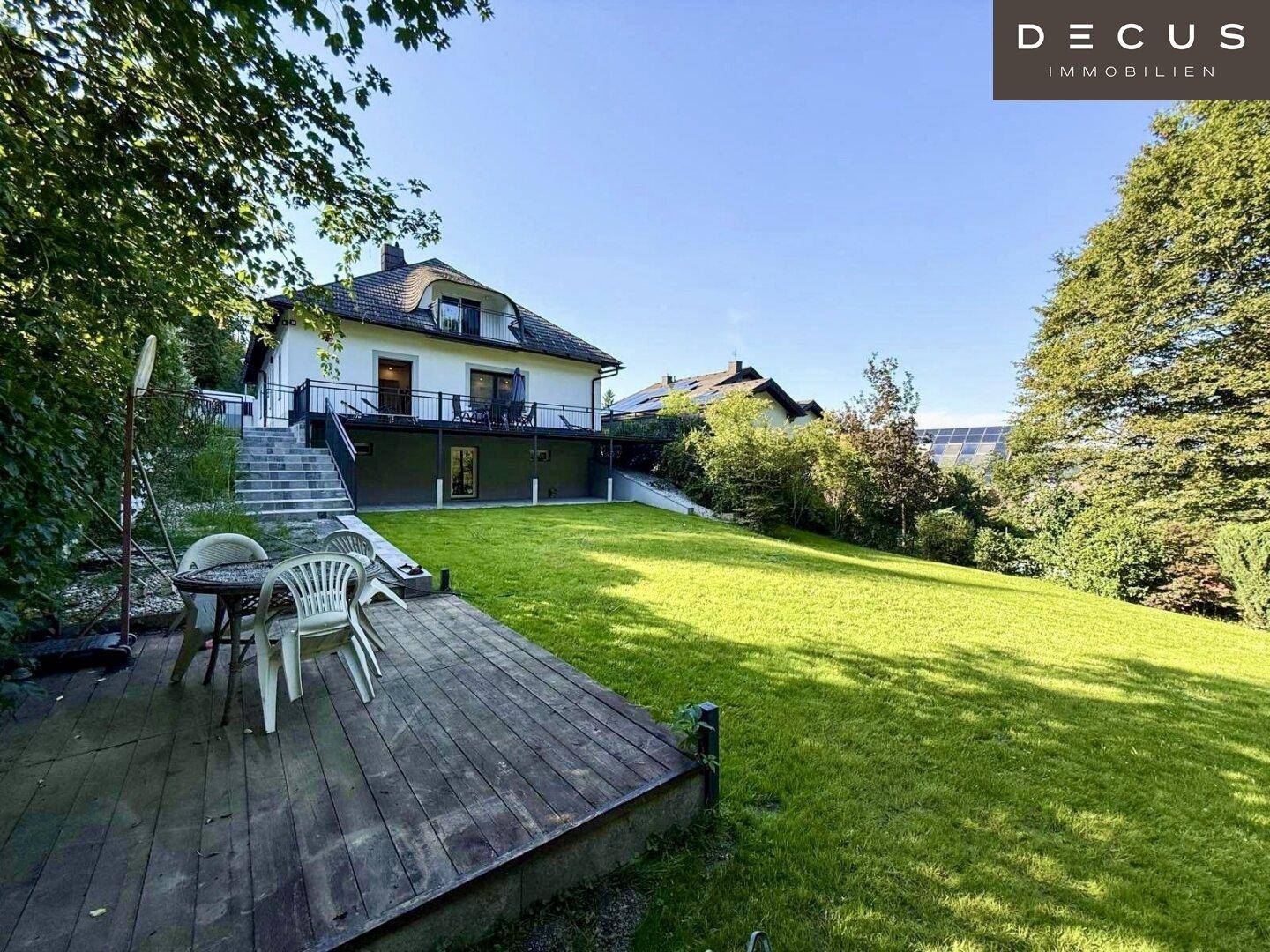 Weitläufiger Garten mit Rasenfläche und Holzdeck für entspannte Stunden.
