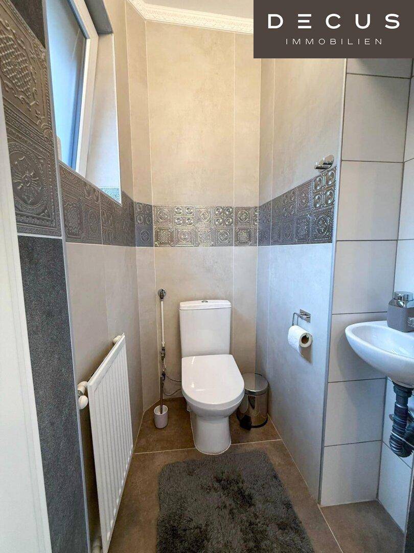 Kleines Gäste-WC mit Fenster, Wand-WC und modern gefliesten Wänden.