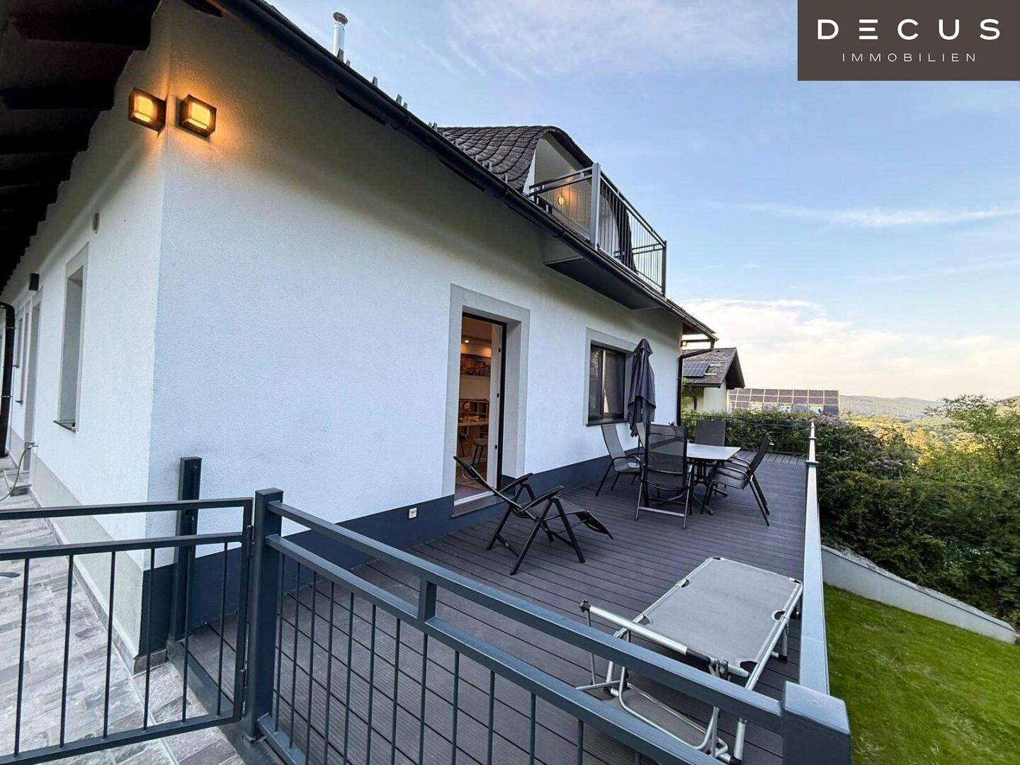 Seitliche Holzterrasse mit Sitzgelegenheiten und weitem Blick in die Landschaft.