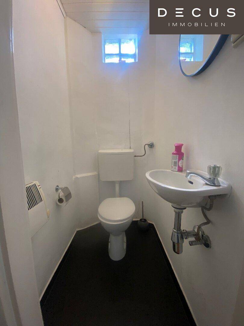 Kleines Gäste-WC mit Toilette, Waschbecken und einem kleinen Fenster für Belüftung.