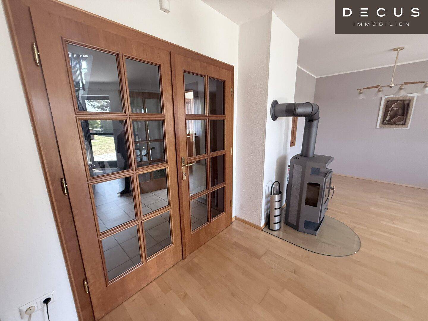 Detailansicht des Kaminofens im Wohnzimmer mit Glastüren und hellem Holzboden.
