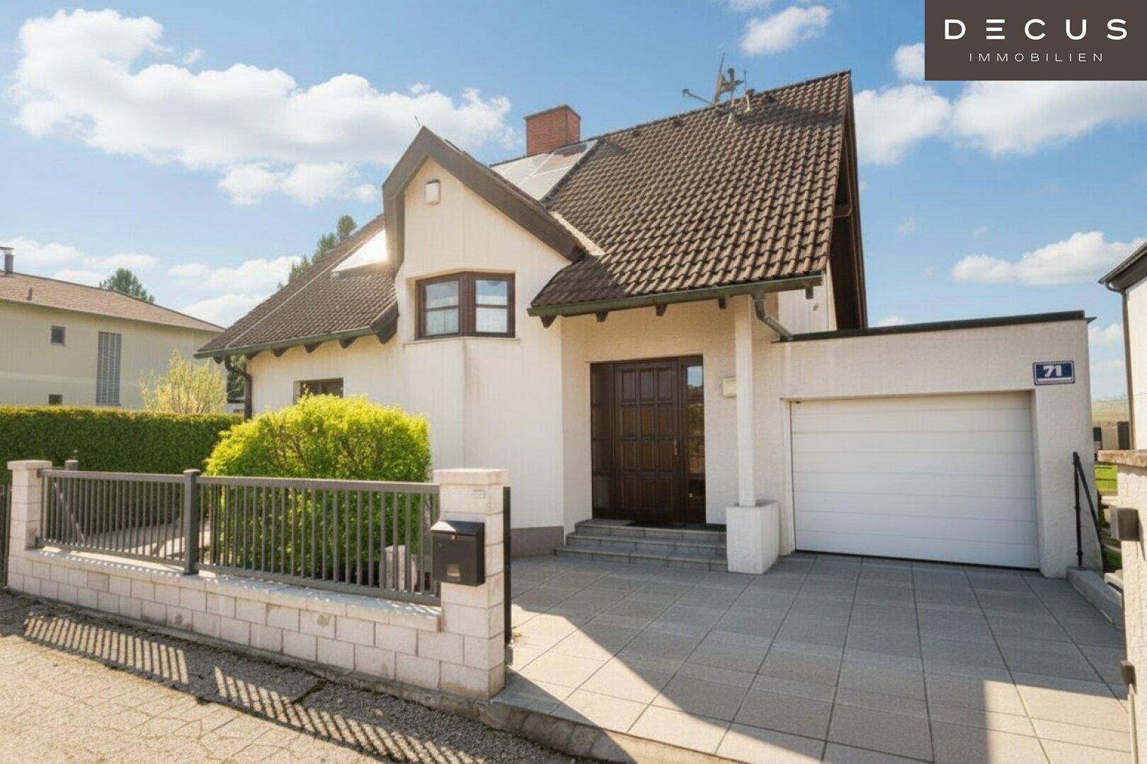 Vorderansicht des Einfamilienhauses mit Garage, gepflasterter Einfahrt und Vorgarten.