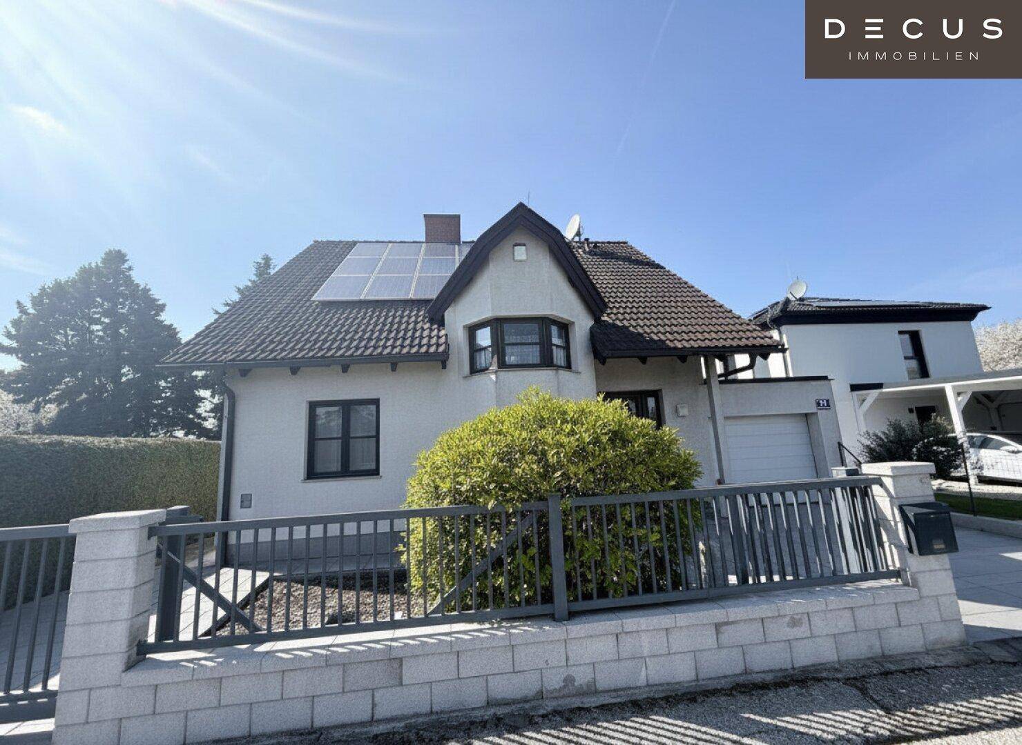 Vorderansicht des Einfamilienhauses mit Zaun, Garage und Solaranlage auf dem Dach.