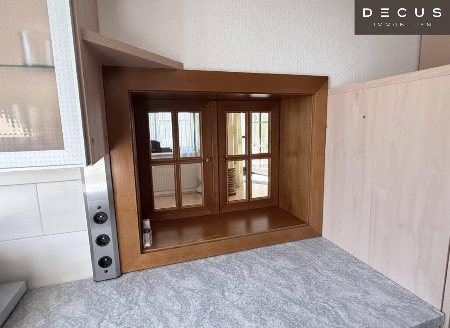 Kleines dekoratives Fenster in einem Innenraum, möglicherweise als Durchreiche oder Zierelement.