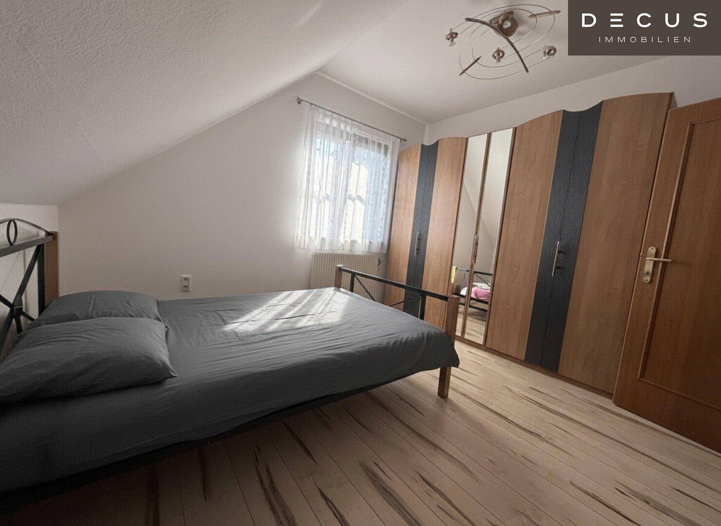 Gemütliches Schlafzimmer mit Bett, großem Kleiderschrank und Dachschräge.