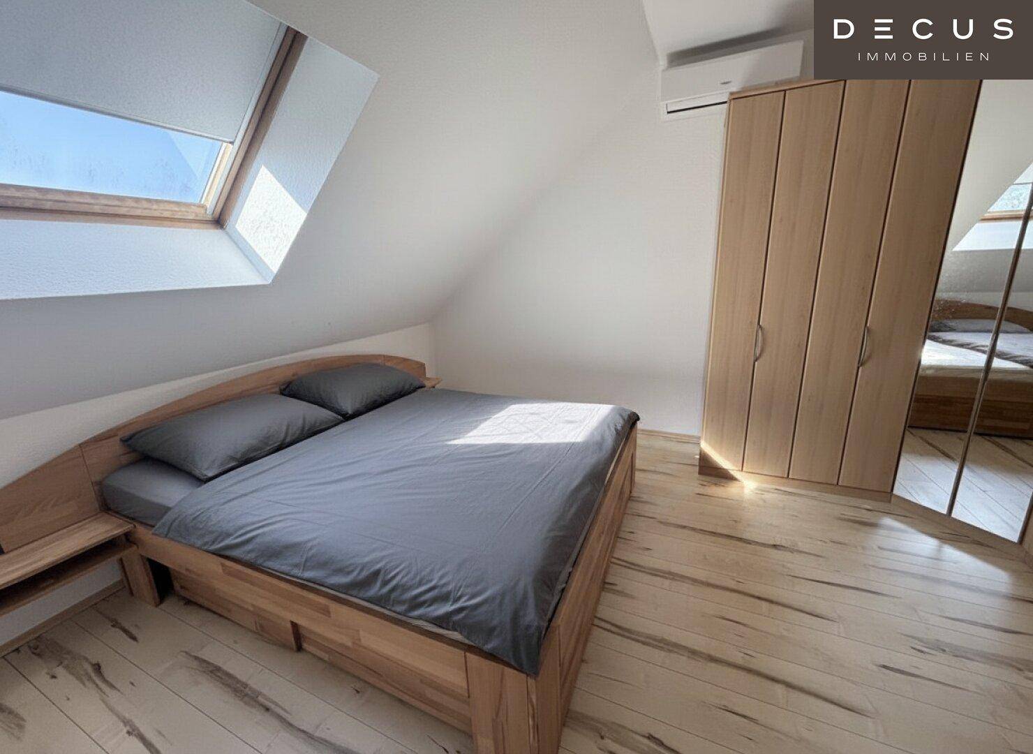 Helles Schlafzimmer mit Holzbett, Kleiderschrank, Dachschräge und Dachfenster.