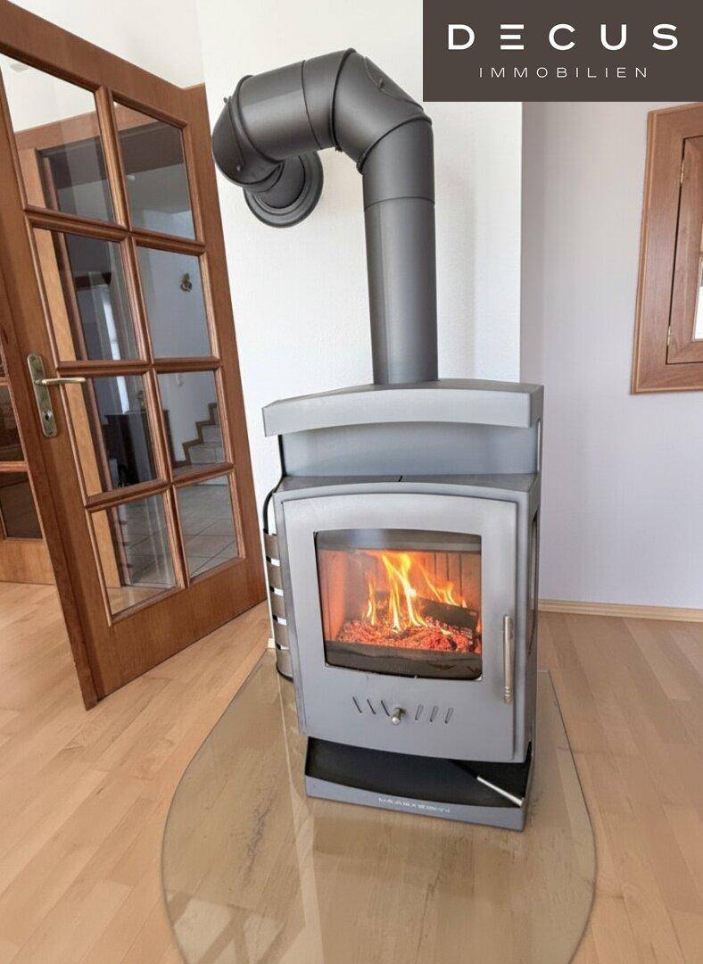 Nahaufnahme des brennenden Kaminofens im Wohnzimmer, der eine gemütliche Atmosphäre schafft.