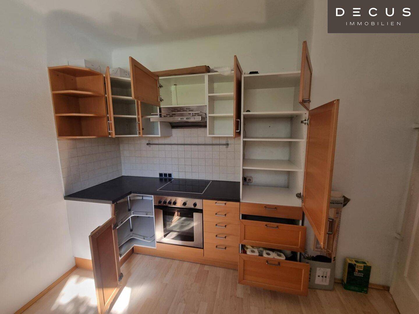 Funktionale Küche mit Holzschränken, integriertem Backofen und Induktionskochfeld.