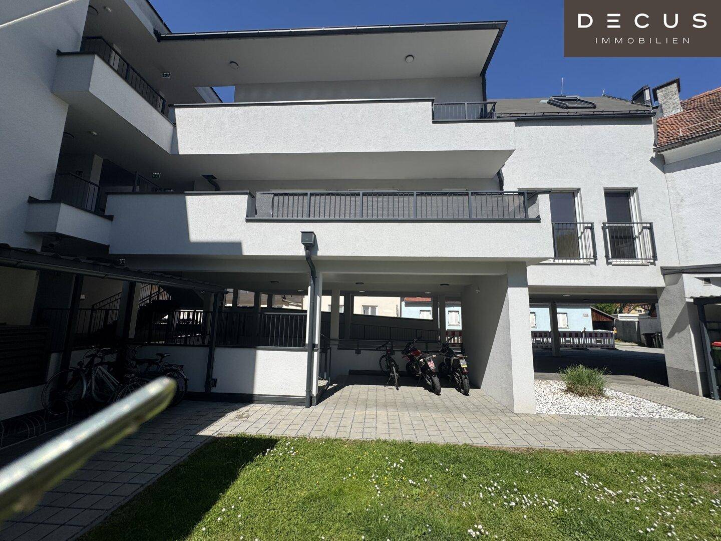 Moderne Wohnanlage mit Außenparkplätzen und Grünflächen im Vordergrund.