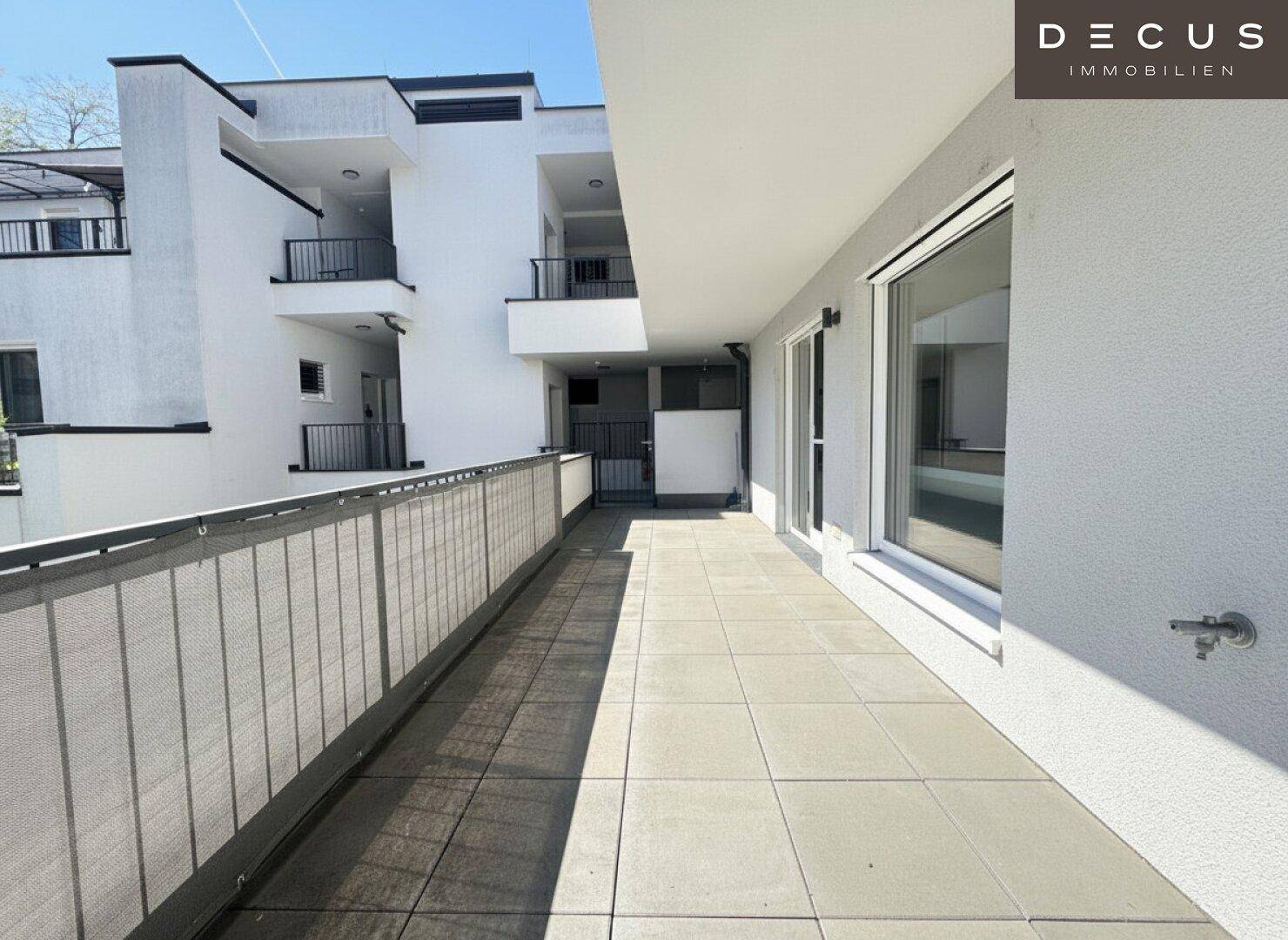 Breiter Balkon mit Fliesenboden und moderner Brüstung, Teil der Gebäudefassade.