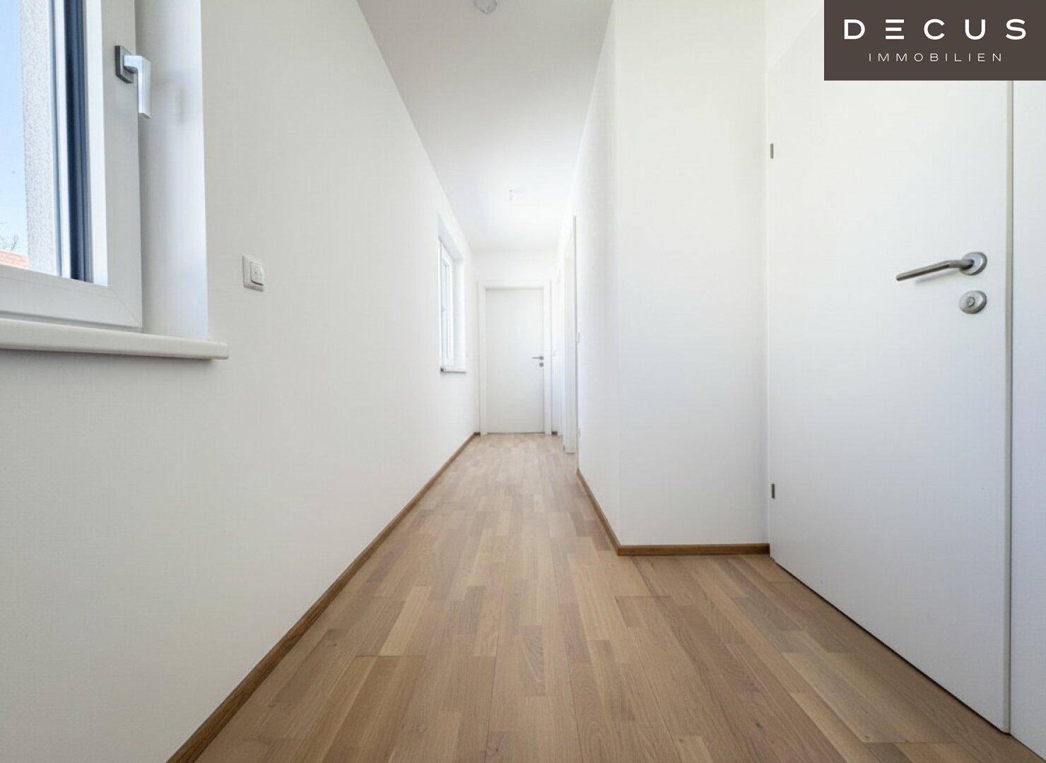 Heller Flur mit Parkettboden, der zu den verschiedenen Räumen der Wohnung führt.