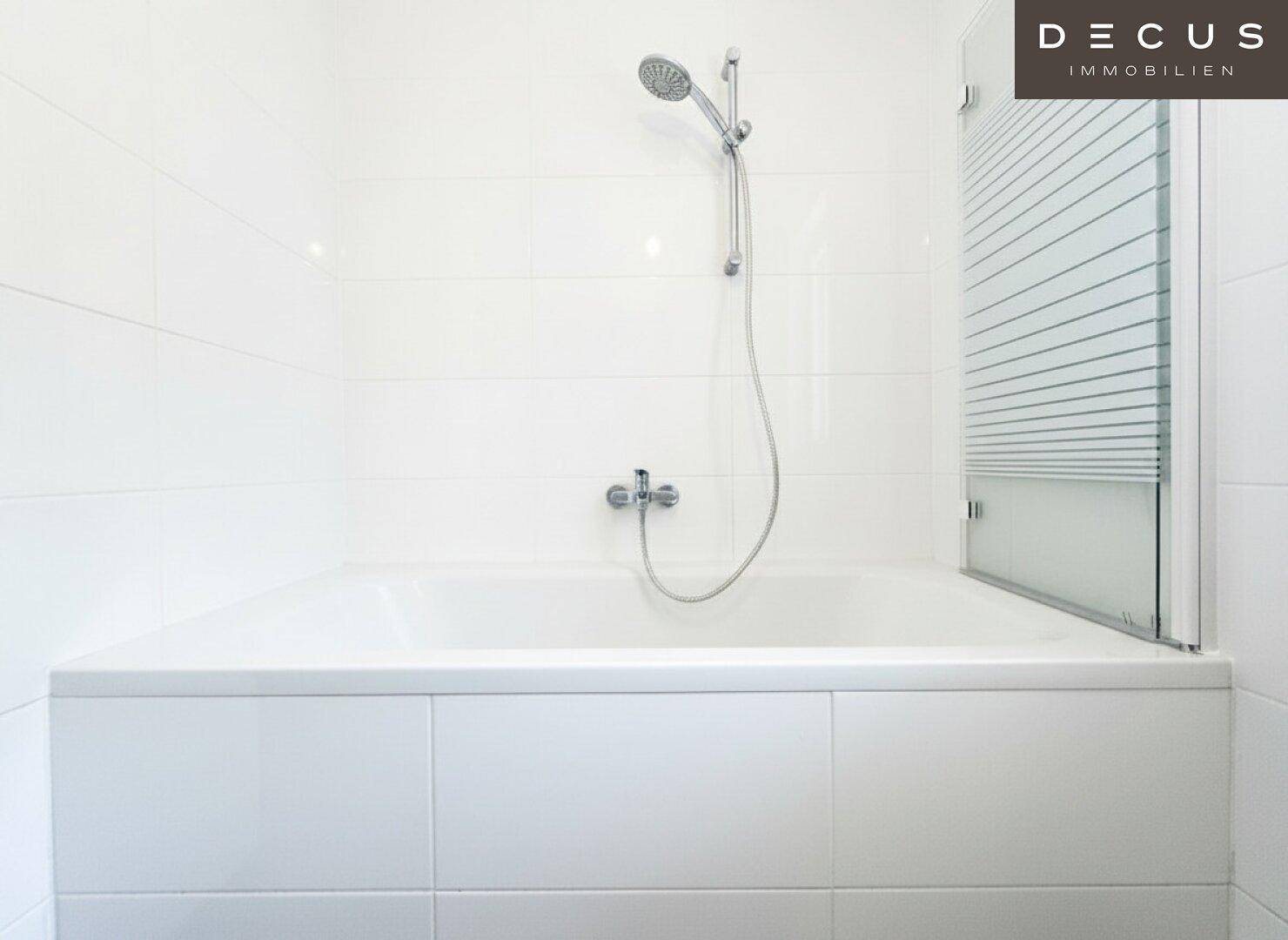 Eingebaute Badewanne mit Duschfunktion und weißer Fliesenverkleidung im Badezimmer.