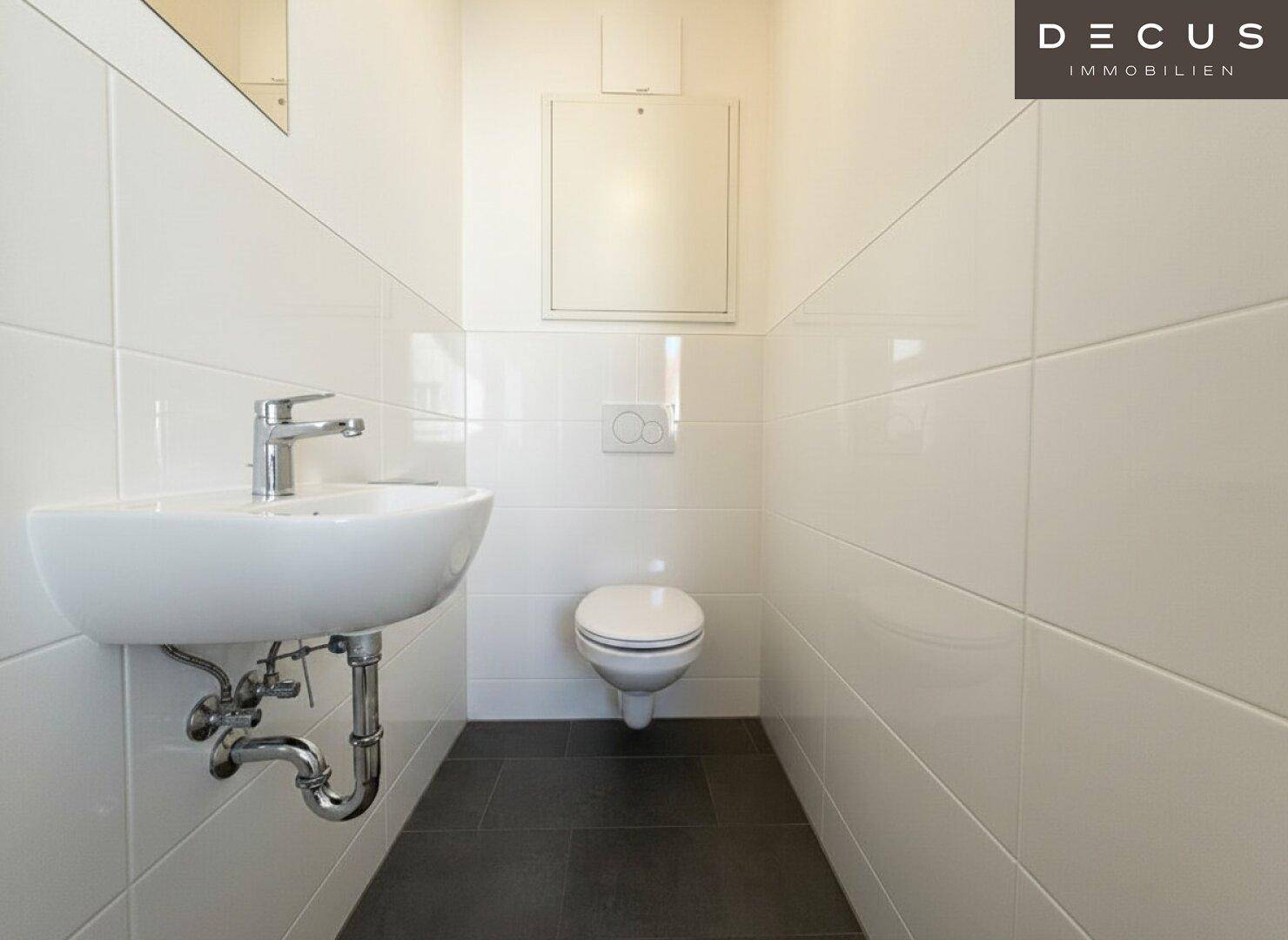 Separates Gäste-WC mit modernem Waschbecken und wandhängender Toilette.