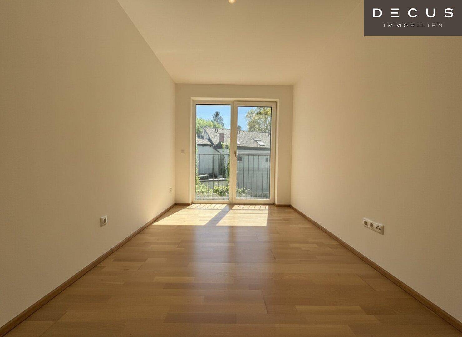 Lichtdurchfluteter Raum mit Parkettboden und breiter Balkontür, ideal als Schlafzimmer.