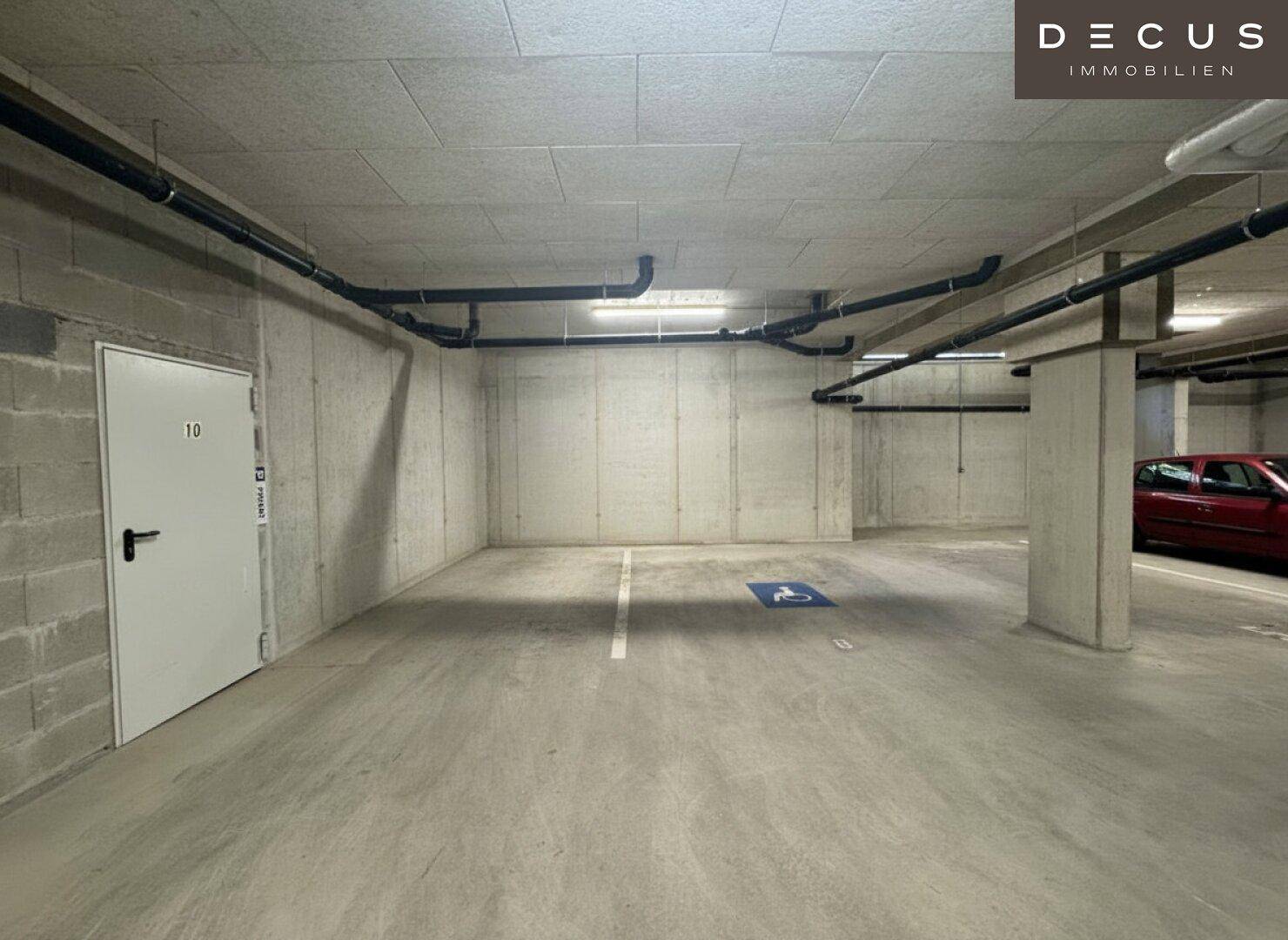 Geräumige Tiefgarage mit Betonwänden und markierten Parkplätzen für Bewohner.
