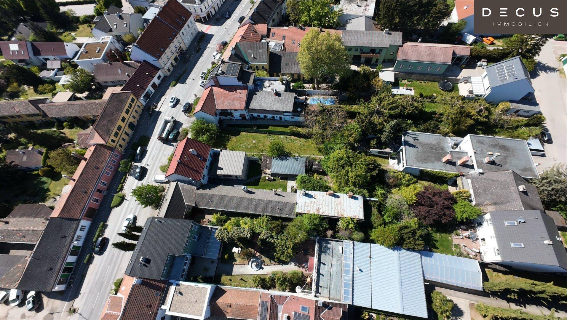 Luftaufnahme eines Wohngebiets mit Häusern, Gärten und Straßen aus der Vogelperspektive.