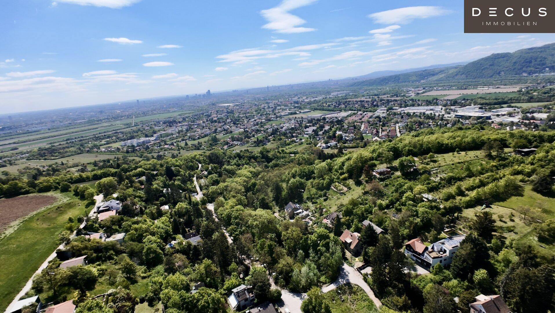Luftaufnahme einer Wohnsiedlung eingebettet in eine weitläufige grüne Landschaft.