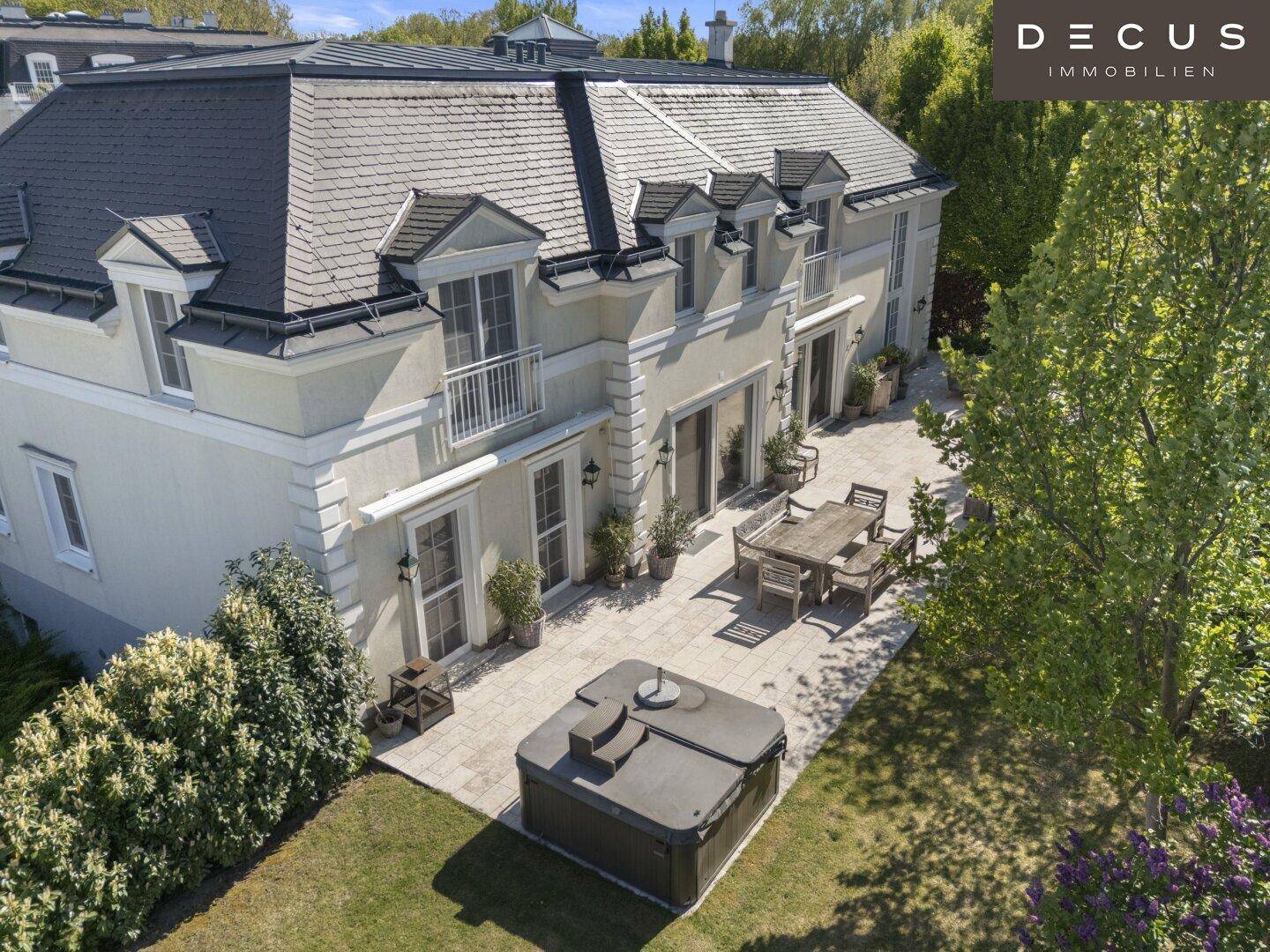 Geräumige Terrasse mit Esstisch, Whirlpool und Blick auf den gepflegten Garten der Villa.