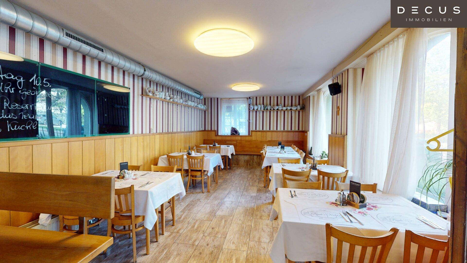 Gastraum mit Holztäfelung, gestreiften Tapeten und einer Tafel für Tagesangebote.