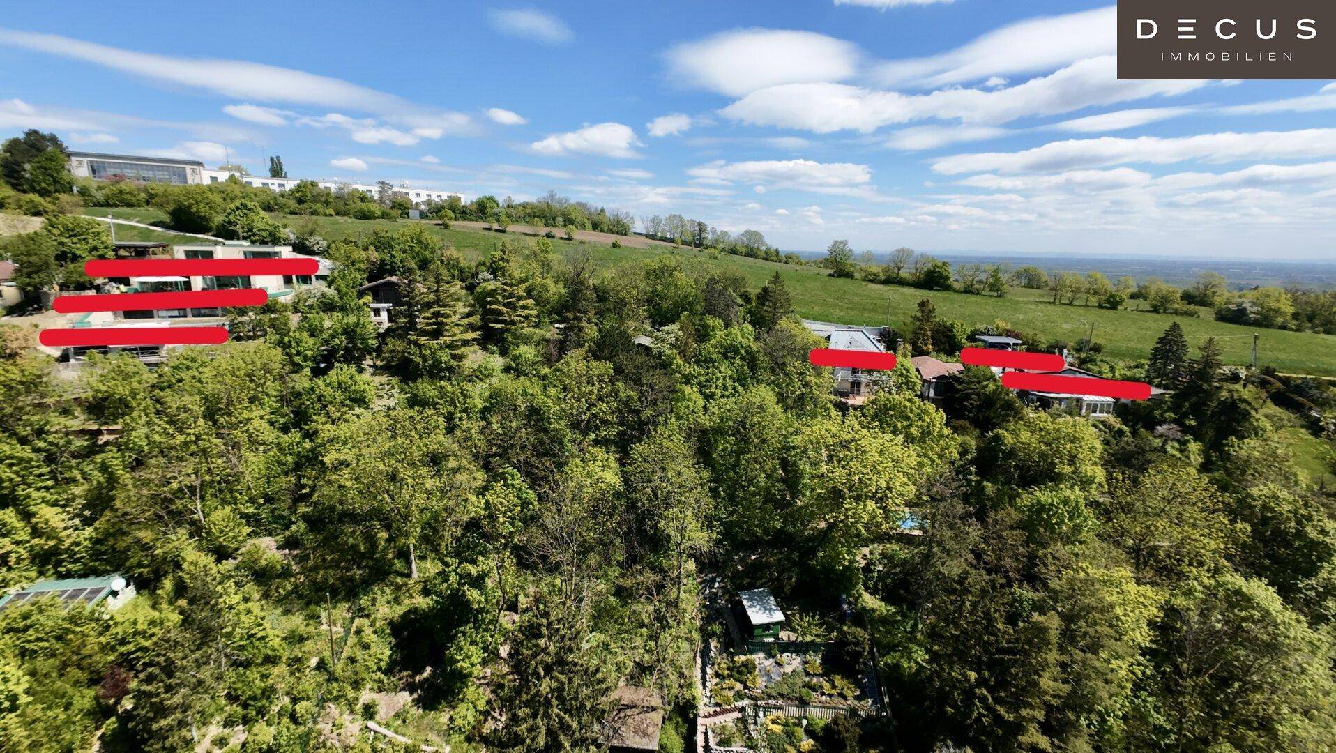 Luftaufnahme einer bewaldeten Hanglage mit mehreren Häusern und weitem Blick.