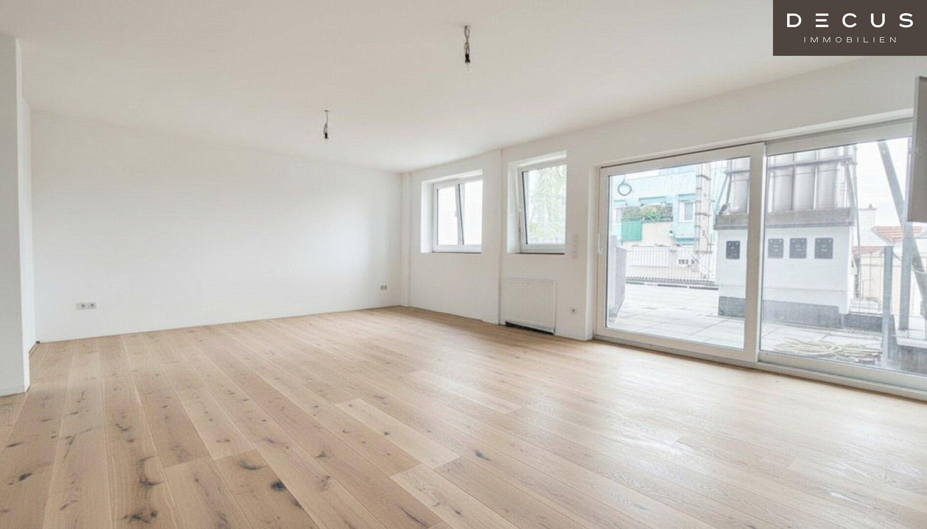 Geräumiger, unmöblierter Wohn-Essbereich mit hellem Parkettboden und großen Schiebetüren zur Terrasse.