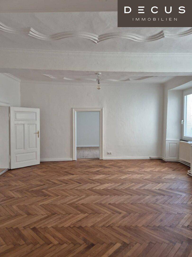 Helles Wohnzimmer mit klassischem Fischgrätparkett und dekorativer Stuckdecke.
