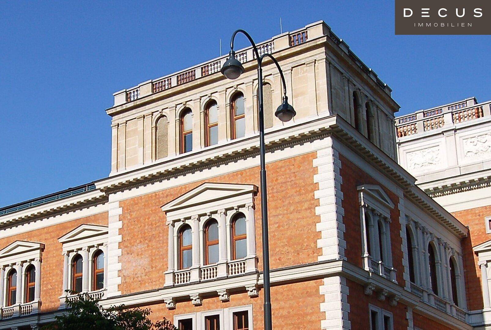Detailansicht der Ecke eines historischen Gebäudes mit verzierten Fenstern und einer Straßenlaterne.